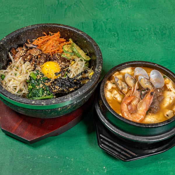 Two Korean dishes: a colorful bibimbap bowl with a raw egg yolk and a seafood tofu soup.
